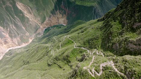 drone shot from the beginning of the path in cabanaconde, revealing the entire descent toward sangalle, with the vast landscape of the colca canyon and the lush oasis of sangalle in the distance.