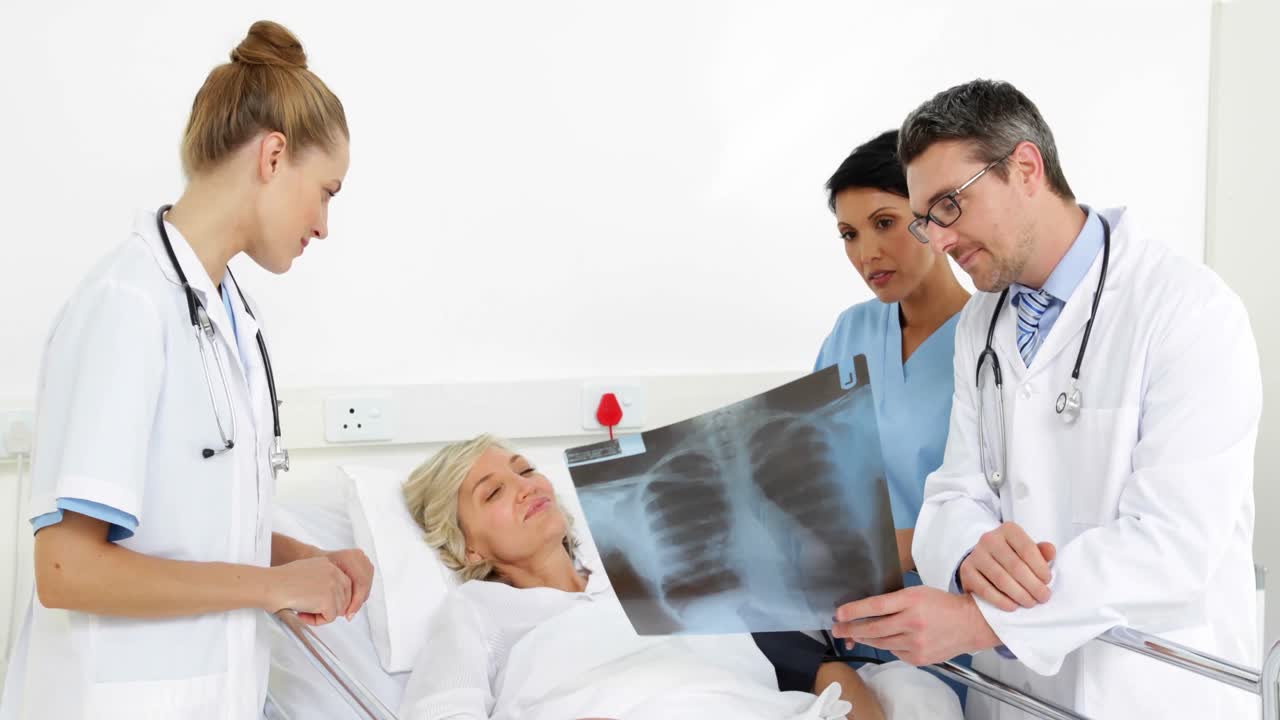 침대에 있는 환자에게  ⁇ 스레이를 설명하는 의사 들