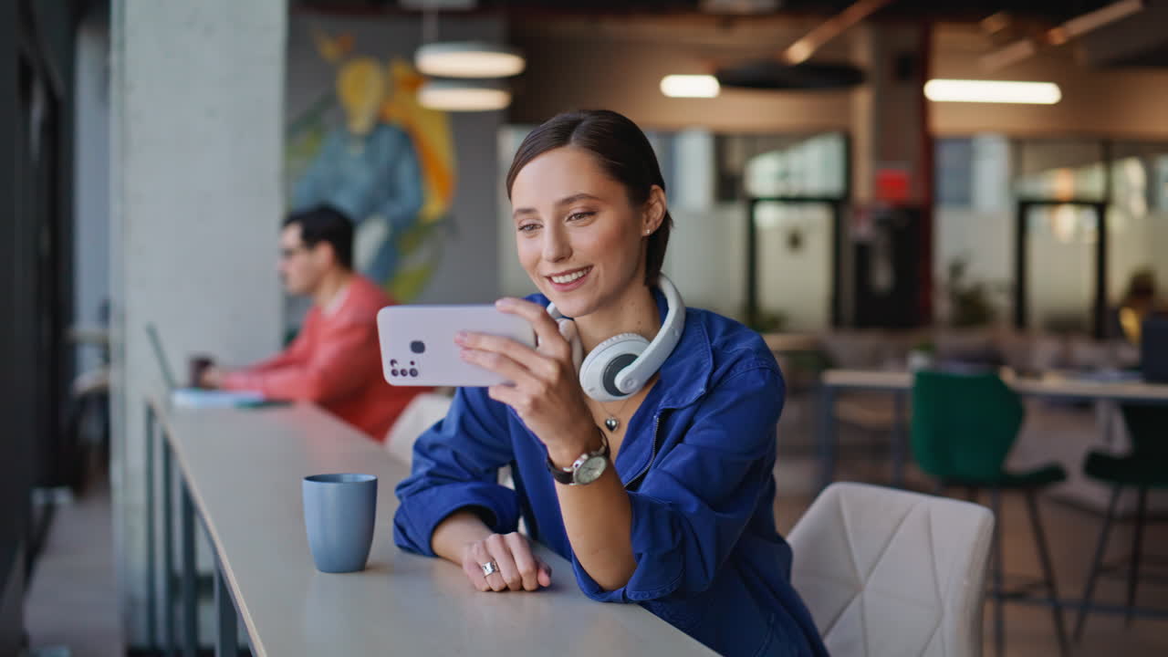 Happy girl watching horizontal cellphone relaxing at modern cafeteria closeup