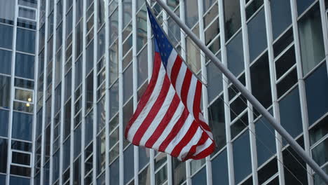 american flag in front of modern skyscrapers