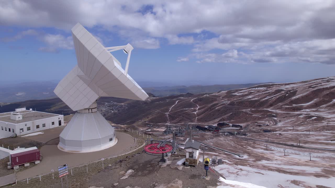 Radio telescope observatory in snowy mountains. Travelling aerial view. Telescope in high mountains. Sierra Nevada. Spain.