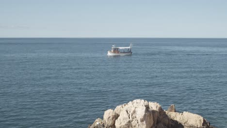 wide shot of fishing boat coming home after fish catch on adriatic sea during sunny day