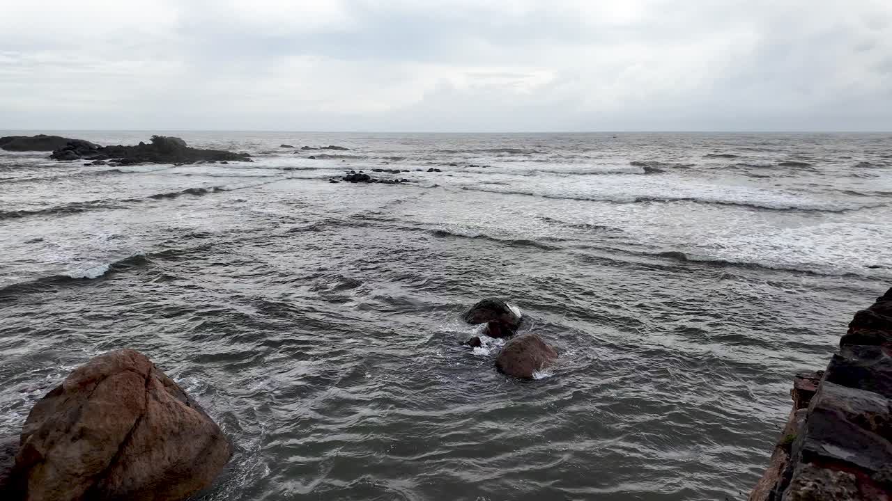 Serene view of powerful ocean waves rolling towards rocky shores near Galle Fort in Sri Lanka, capturing the essence of nature's beauty and tranquility.