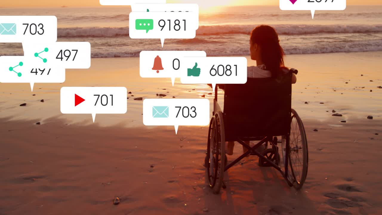 Una mujer empuja una silla de ruedas sobre la arena al atardecer mientras observa alertas tecnológicas flotando, agrupándose y luego desapareciendo.