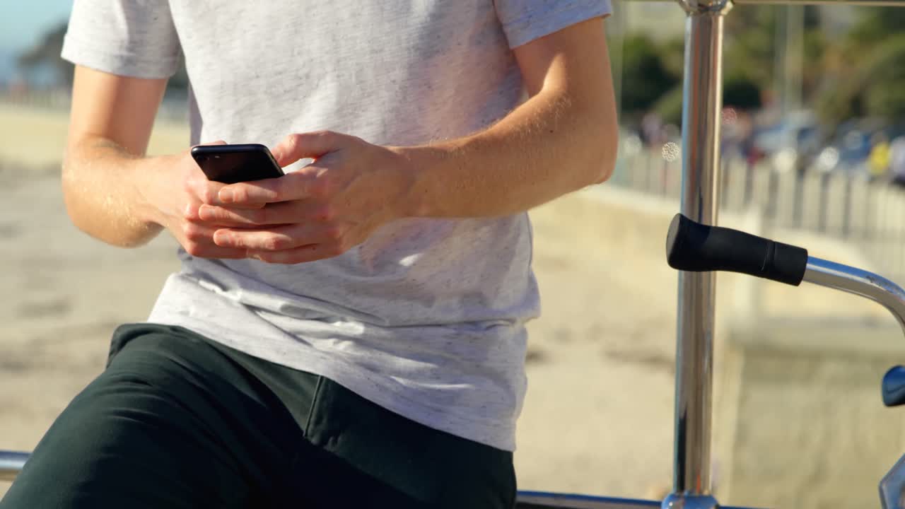 해변 4k에서 휴대 전화를 사용하는 자전거를 타고 있는 남자