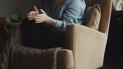 red haired woman sitting on the sofa raises her bulldog dog on top of her legs and gives him caresses and kisses