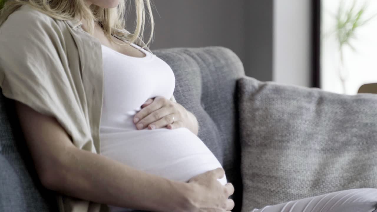 улыбающаяся беременная женщина глубоко дышит.