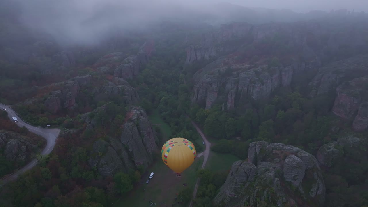 Mongolfiera si libra sopra formazioni mistiche e nebbia di montagna, Bulgaria