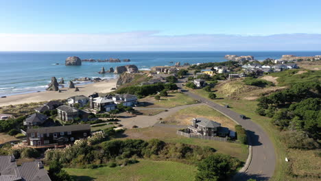 aerial view of the modern houses at bandon city in oregon with turquoise water and glorious trees during sunny day - aerial shot