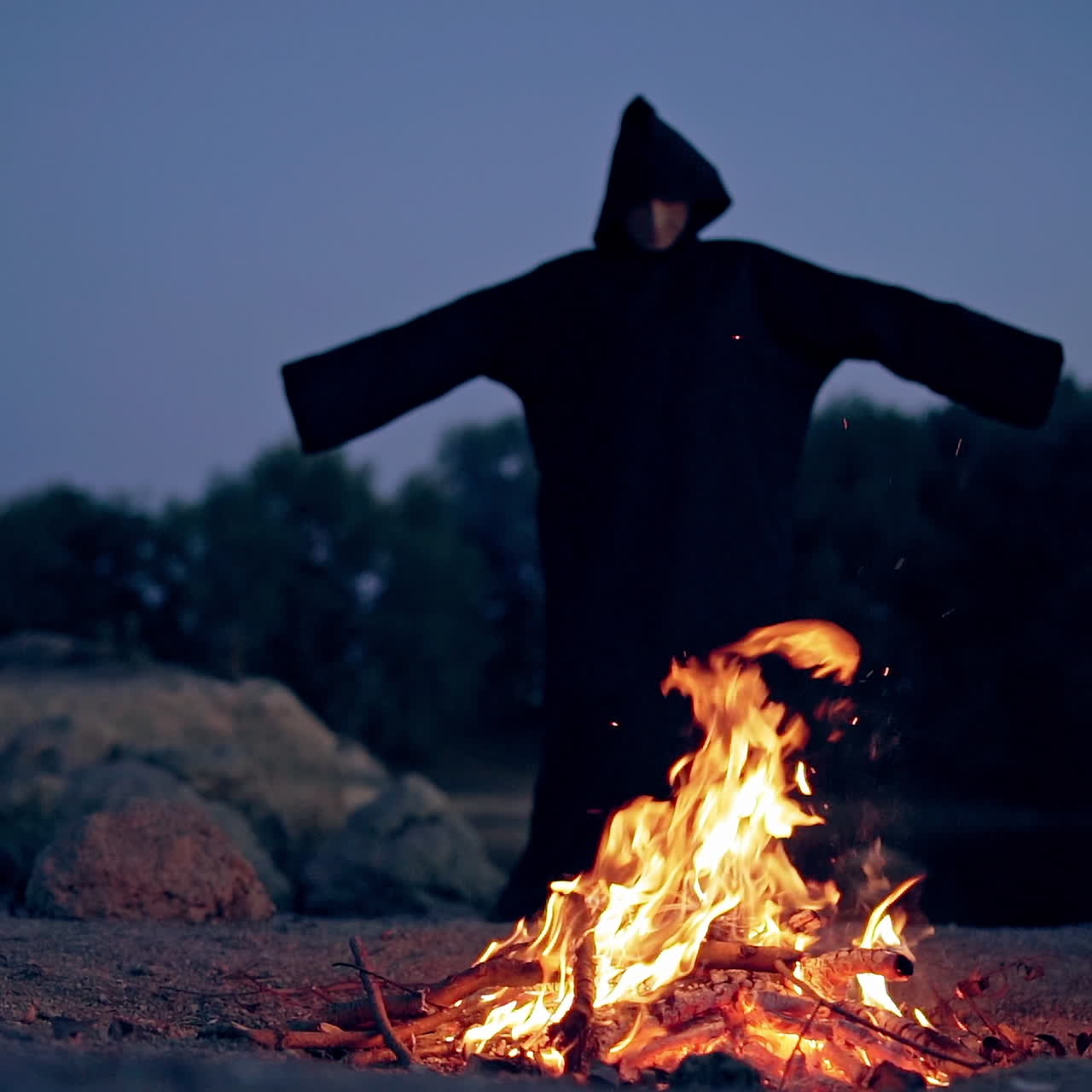 The wicked witch performs a ritual near a bonfire in the night. Mysticism of Halloween