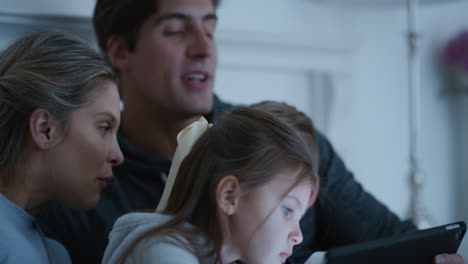 family using tablet computer mother and father watching children playing games on touchscreen device learning having fun together at home before bedtime 4k footage