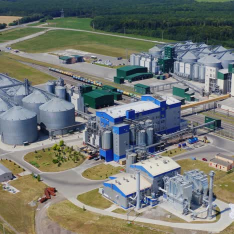 modern plant for agribusiness. industrial area among green nature in summer. metal grain elevators for storing cereals. aerial view.