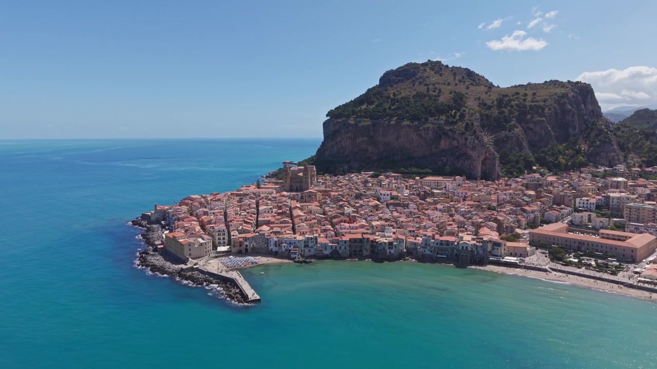Una vista aerea mozzafiato di una città costiera mediterranea circondata da acqua turchese cristallina e scogliere montuose spettacolari.