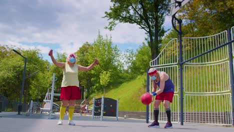 Aktiver-älterer-Mann-Und-Frau,-Die-Während-Des-Coronavirus-Im-Freien-Auf-Einem-Sportplatz-Basketball-Spielt