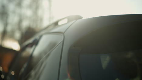 close-up view of a black car with its trunk being opened, set against a softly blurred outdoor background