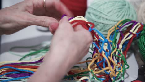 hands making colorful thread knots