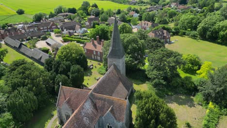 an aerial pull-out shot over ickham village, pulling away to reveal st john the evangelist church