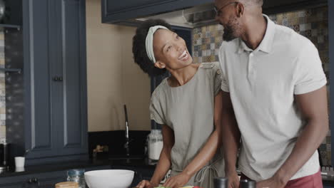 feliz pareja afroamericana hablando y cocinando juntos en la cocina en cámara lenta