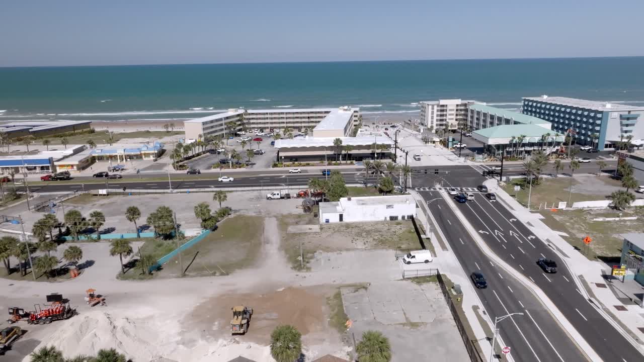 Daytona Beach, Florida with waves from the Atlantic Ocean, vehicles, hotels and people on the beach with drone video moving up