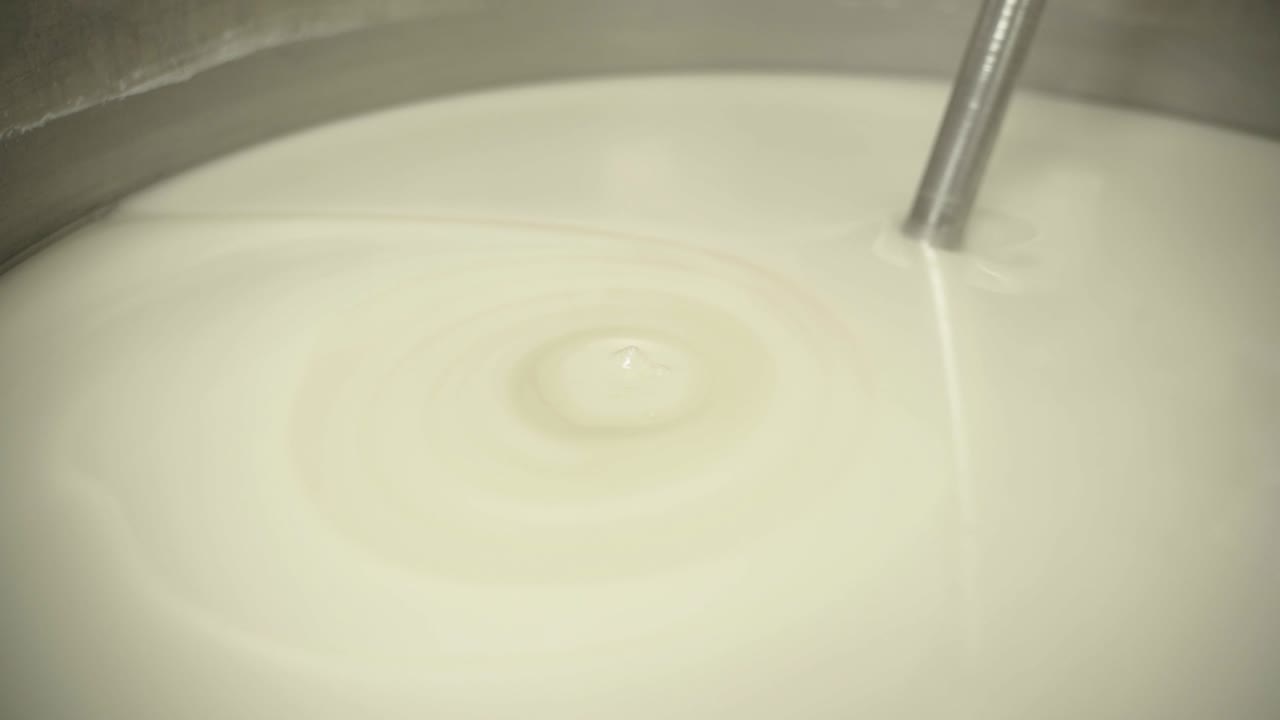 Close-up view of white liquid mixing during pharmaceutical formulation.