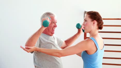 Older-man-lifting-hand-weights-with-the-help-of-his-physiotherapist-