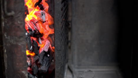 Panning-shot-of-red-hot-burning-flaming-charcoal-in-an-old-rusted-restaurant-grill