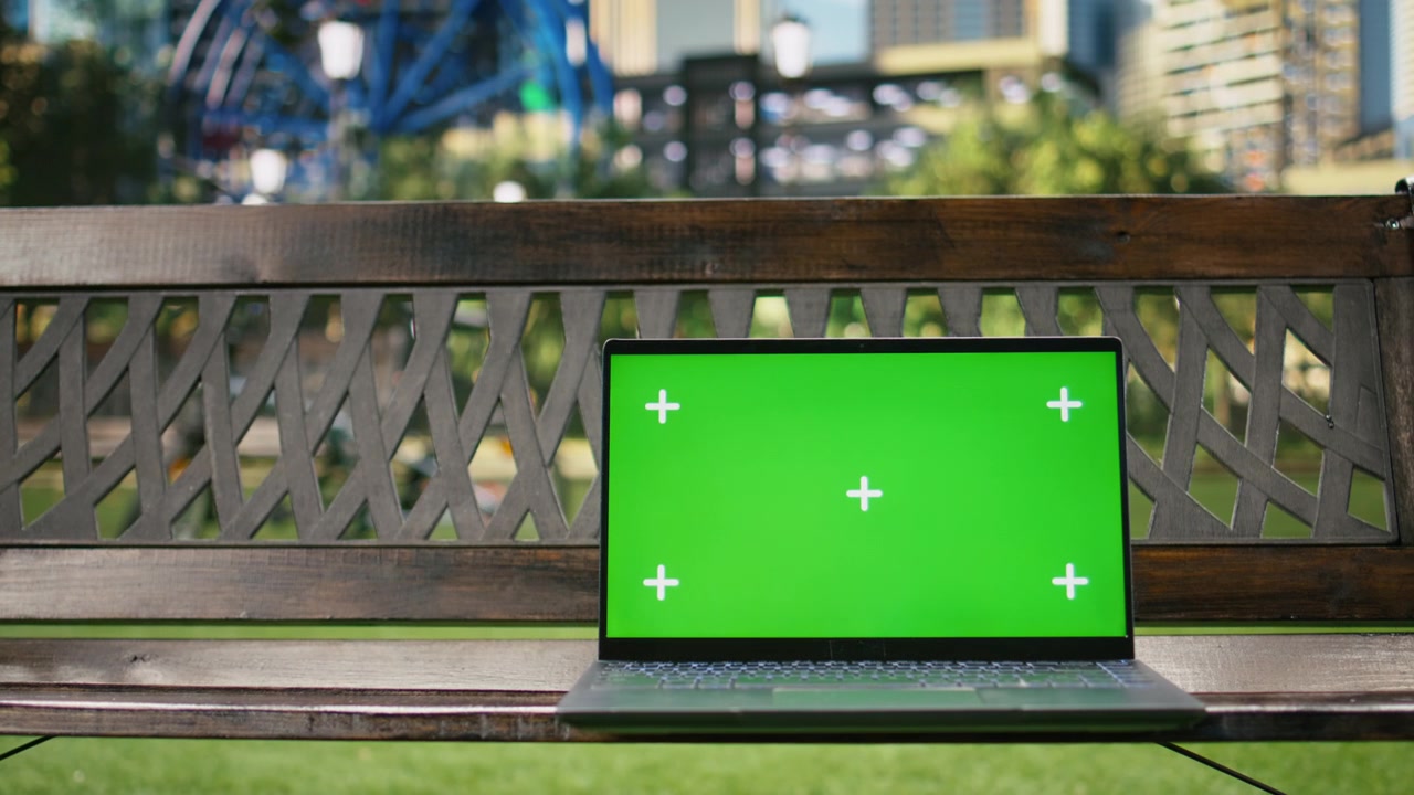 Schermo sostituibile con chroma key su laptop in un parco urbano con grattacieli