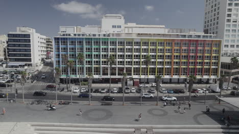 Disparo-De-Drones-Deslizantes-Frente-Al-Colorido-Hotel-Dan-En-Tel-Aviv,-El-Edificio-Rainbow-En-El-Paseo-Gordon-Y-La-Playa-Frishman-Llena-De-Visitantes-En-Un-Cálido-Y-Tranquilo-Día-De-Verano.