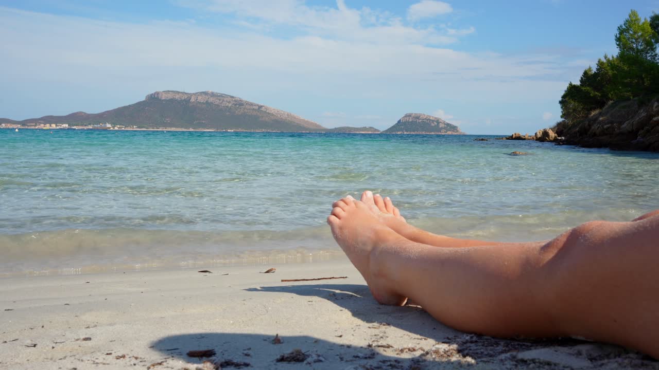 Lady sitting on a sandy tropical beach with perfectly manicured toes