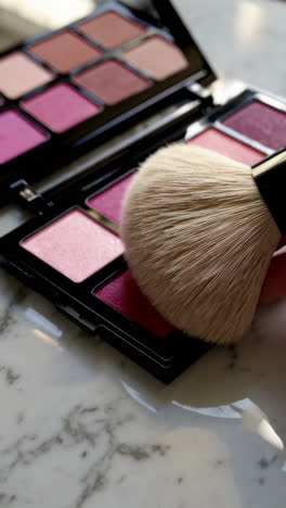 makeup palette and brushes on marble surface