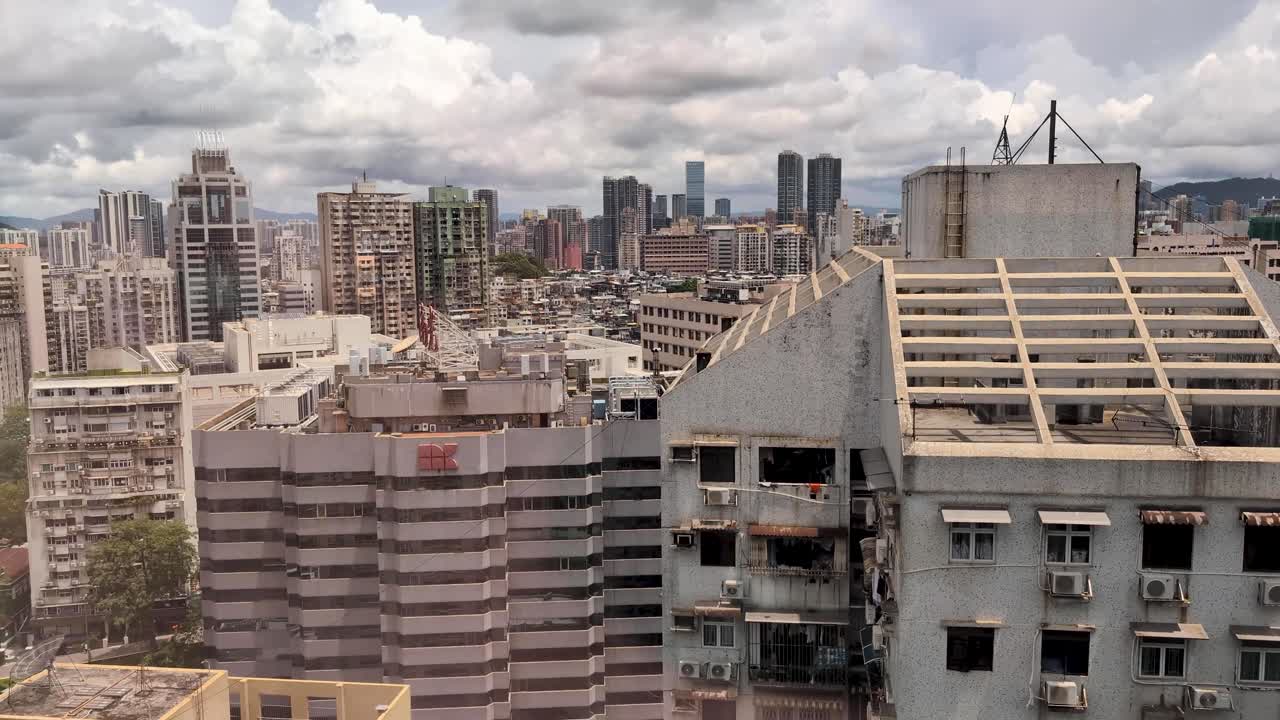 Slow upward pan of crowded Macau cityscape buildings on warm, overcast day from high floor