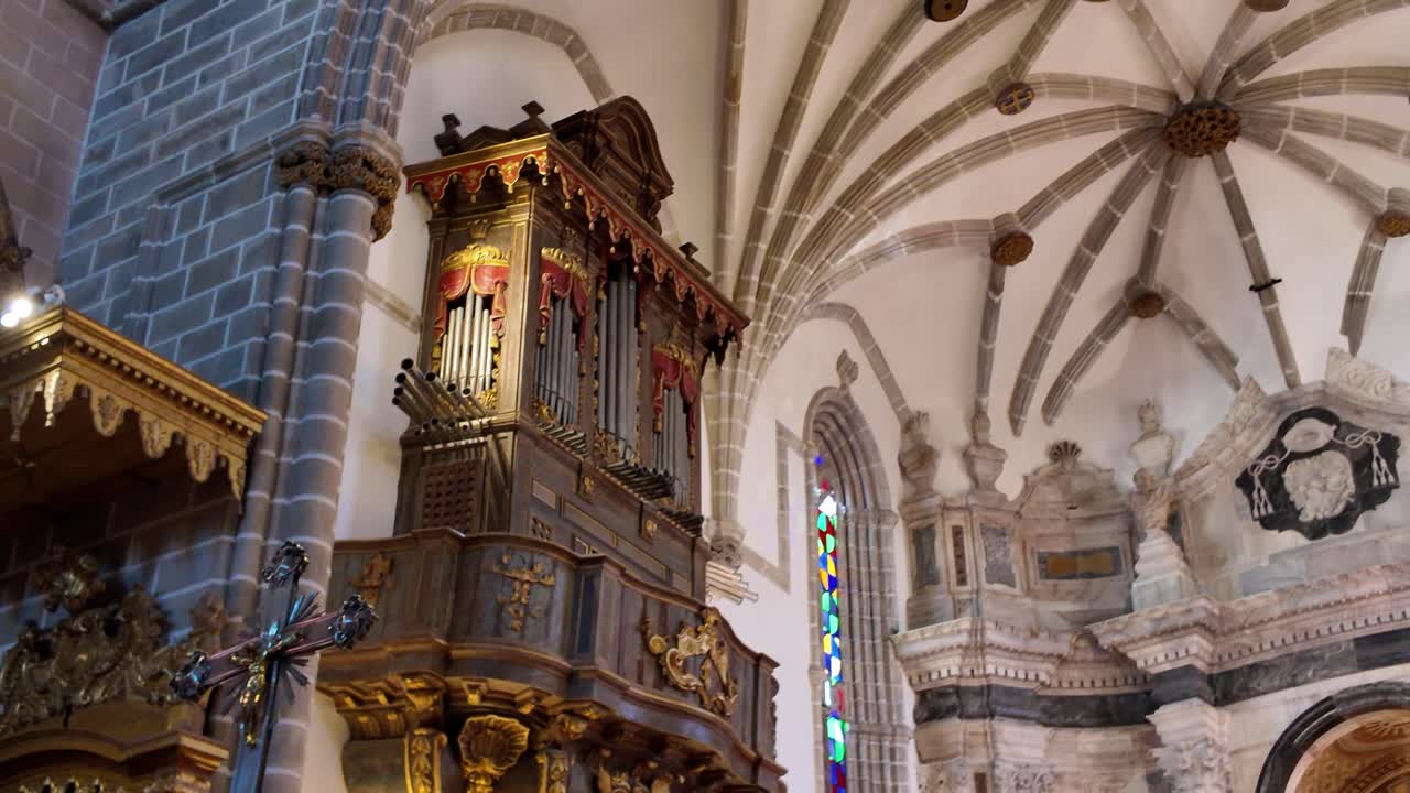 Golden pipe organ and vaulted ceiling in richly decorated historic church interior