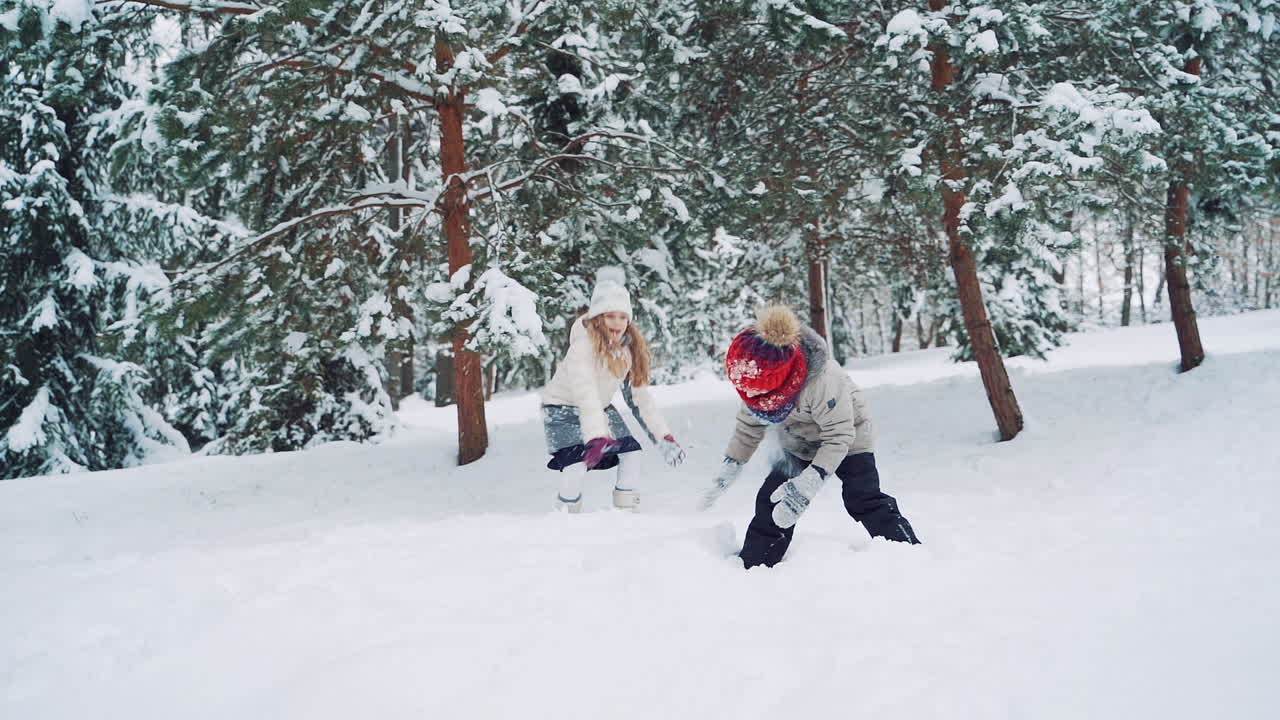 Outdoor family fun on Christmas vacation. Boy and girl play snowballs. Winter clothing. Slow motion.