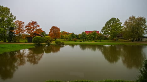 Toma-De-Lapso-De-Tiempo-Del-Amanecer-Nublado-En-El-Lago-Natural-Con-árboles-Coloridos-En-El-Fondo-Durante-El-Día-De-Otoño