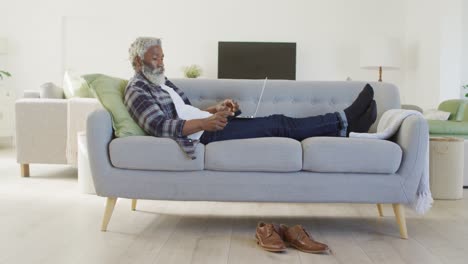 senior man talking on smartphone while using laptop at home