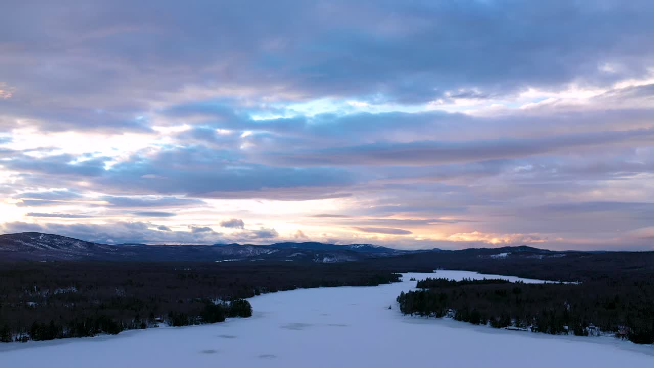 diapositiva aérea a la izquierda sobre un lago congelado al atardecer con nubes dramáticas