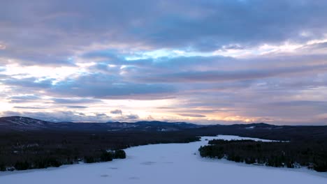 Luftrutsche-Nach-Links-über-Einen-Zugefrorenen-See-Bei-Sonnenuntergang-Mit-Dramatischen-Wolken
