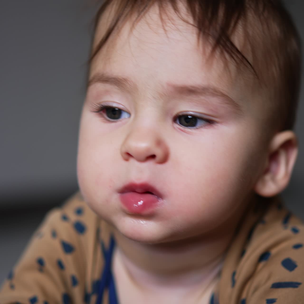 Lovely sweet kid lies on his belly holding a toy in his mouth. Funny baby chewing toys to scratch his gums. Close up