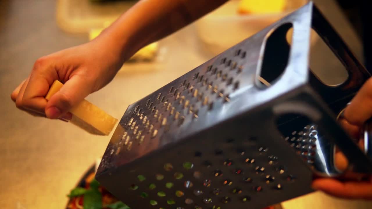 Mano che grattugia Parmigiano fresco sulla pizza.