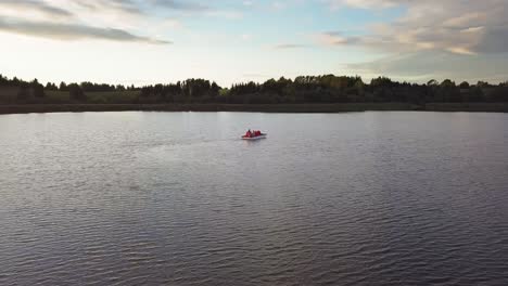 family on a pedal boat on a lake at sunset drone shot