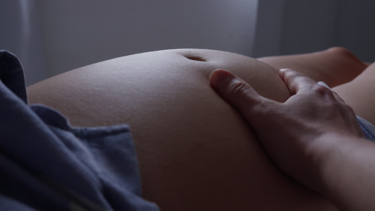 Papà che accarezza il ventre incinta di sua moglie in casa.