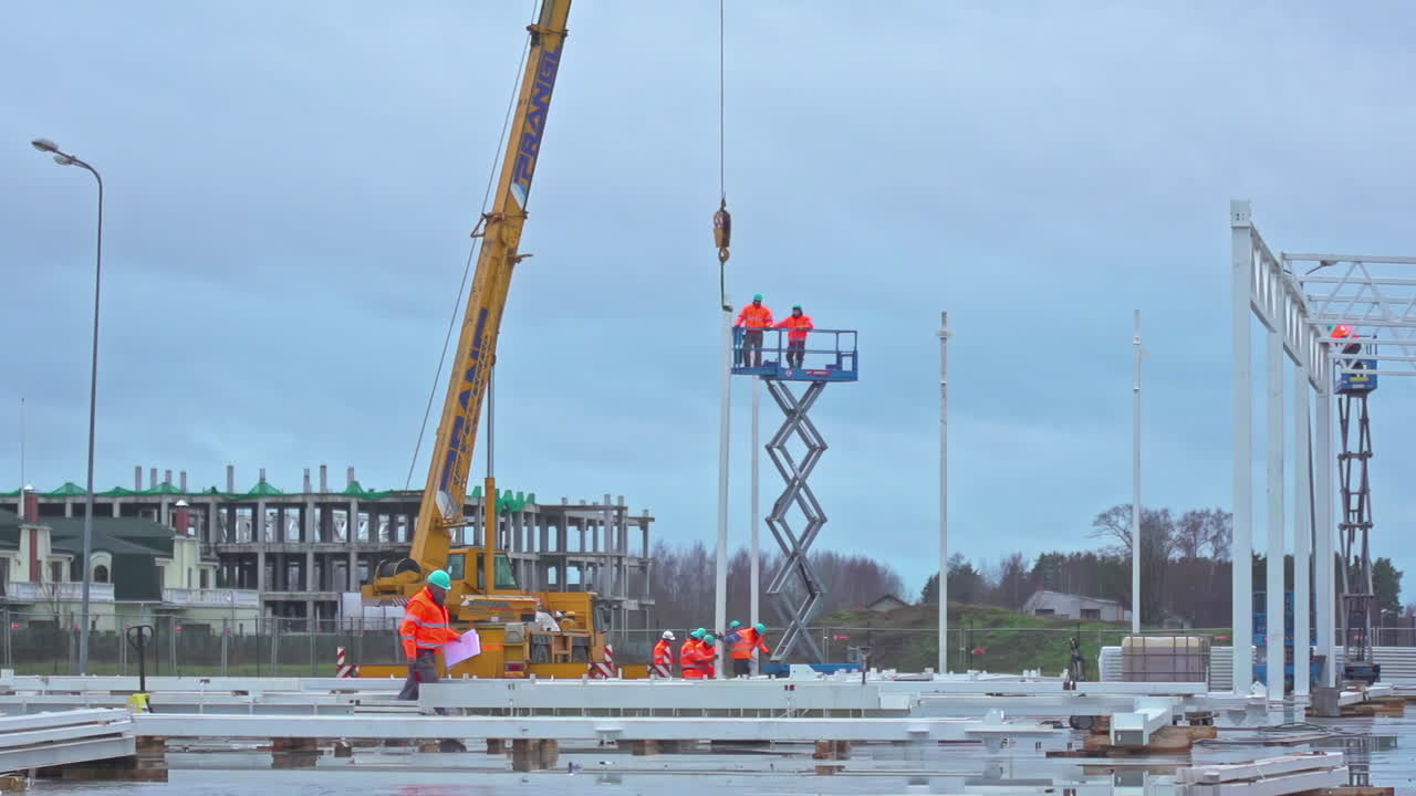 Workers in orange clothing working on a construction site on a high-rise crane