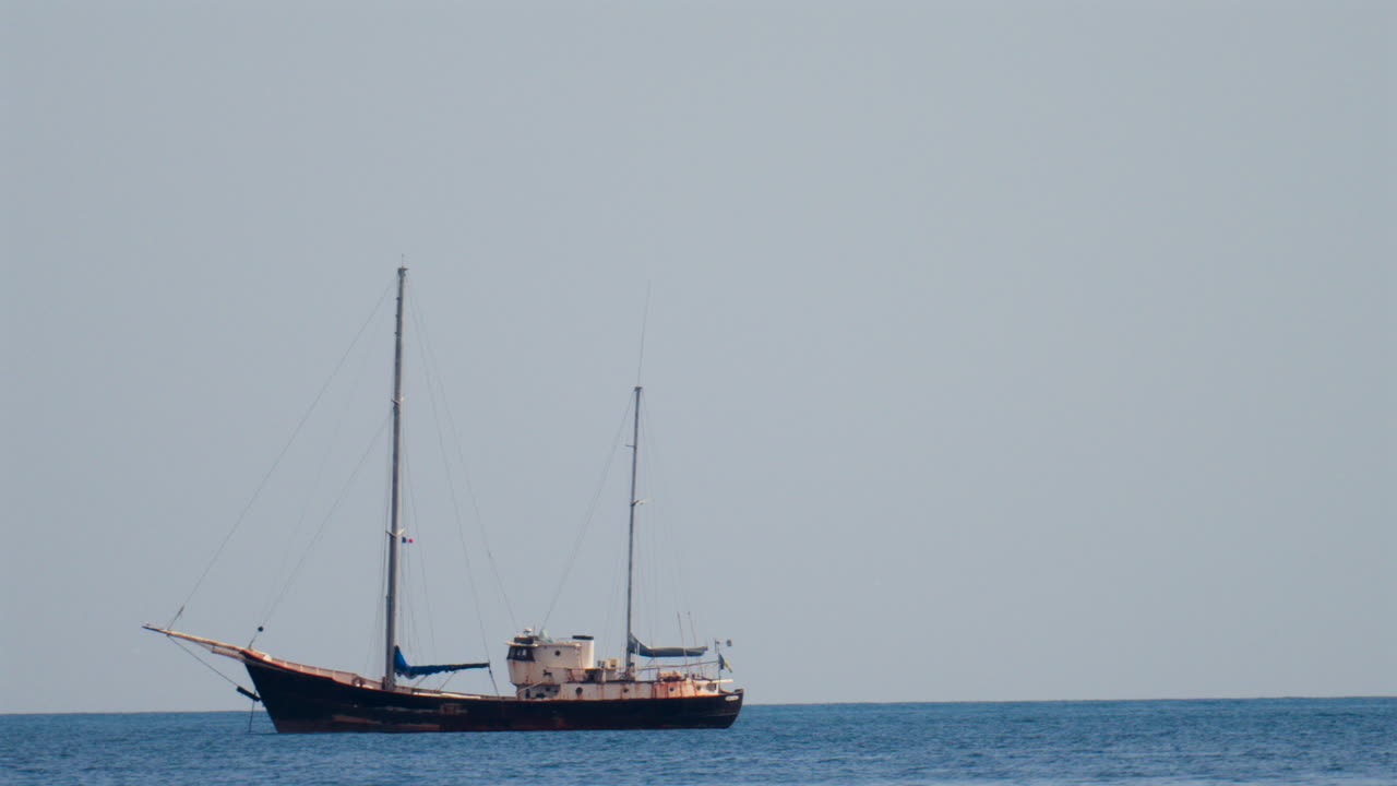 Distant view of a rusty boat moving on the sea in the south of France, on a cloudy day