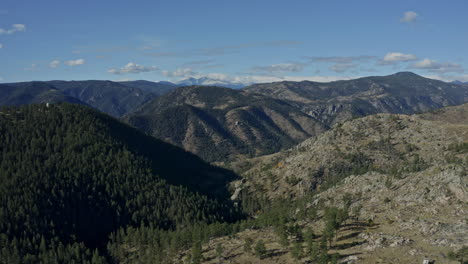 descending aerial looking out over hills and valleys of rocky mountains, 4k