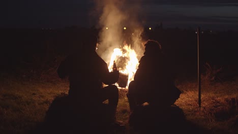 big campfire conversation of 2 men, dark night