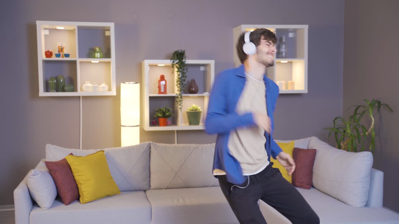Happy young man in headphones and listens to music from music app and dances.