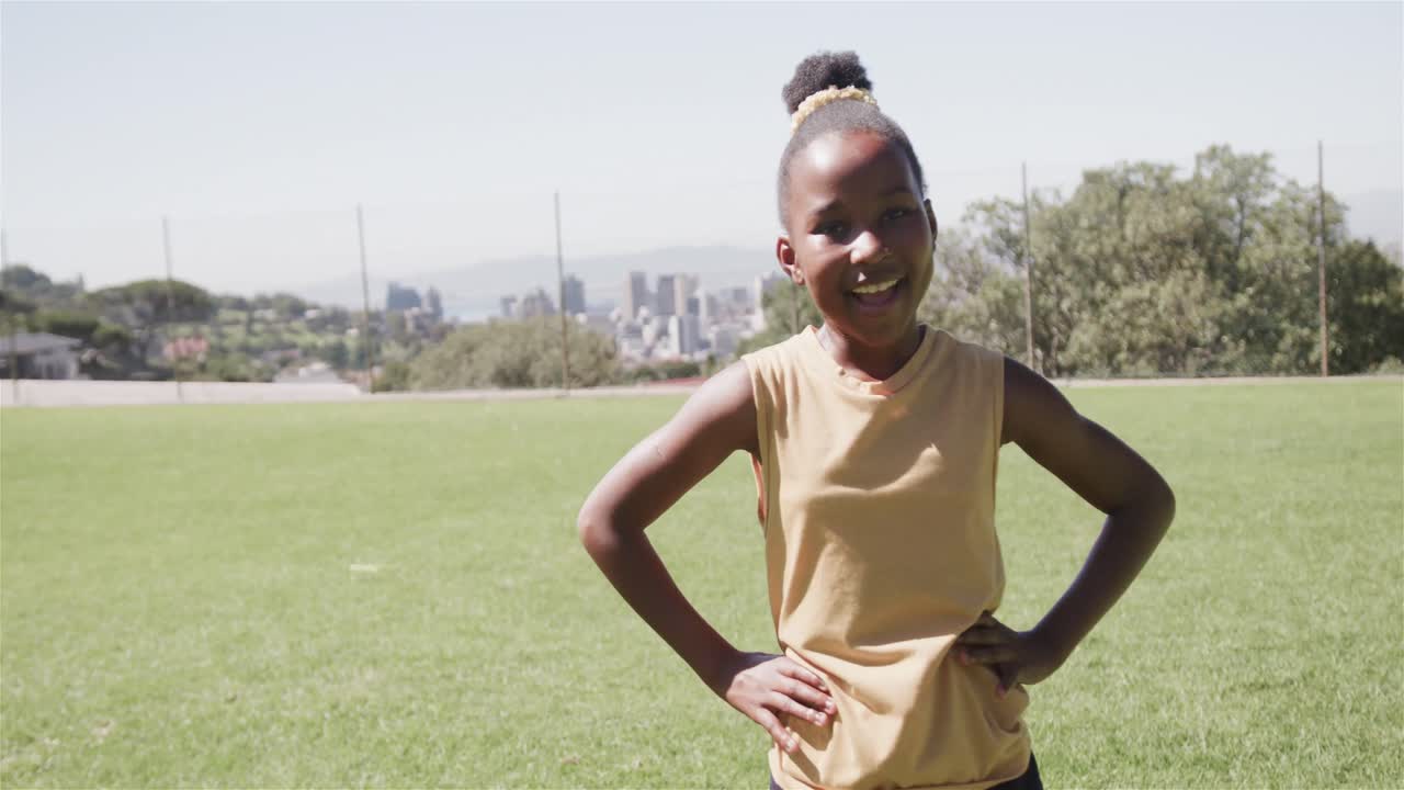 Portrait of happy african american girl on sunny elementary school playing field, slow motion