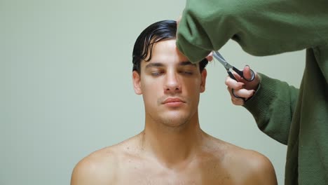 wife cutting hair of her husband inside the house