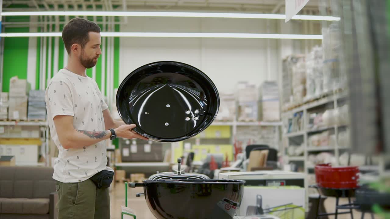 Man Inspecting a Grill in a Retail Store
