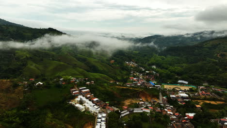 drone disparado elevándose sobre la ciudad y el río en las montañas de san rafael, colombia nublada
